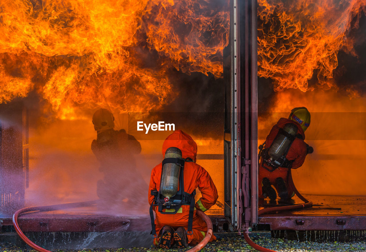 Rear view of firefighters spraying water