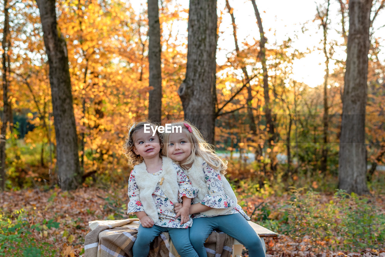 Low angle view of girl in forest during autumn