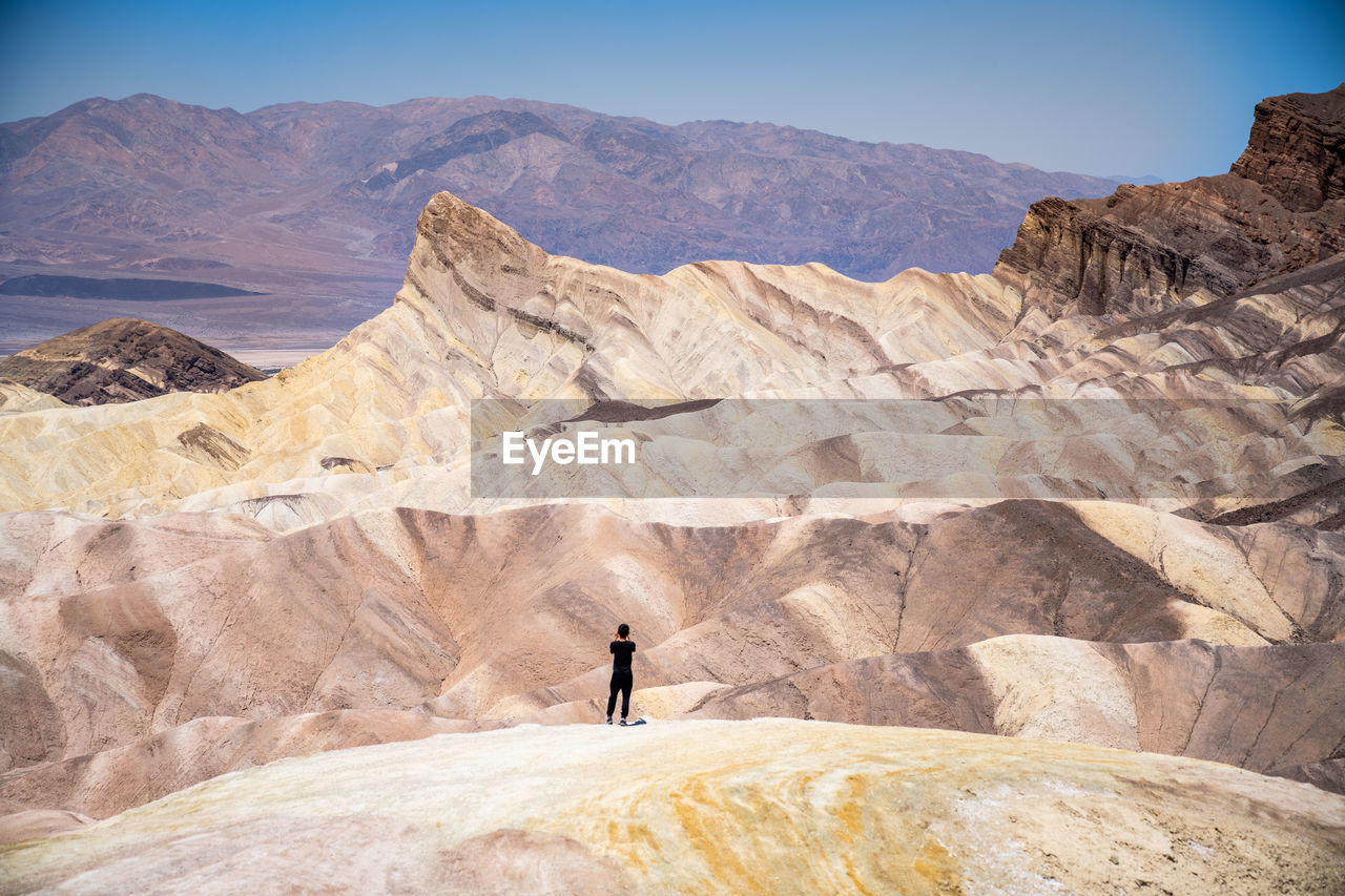 rear view of man standing on rock formations