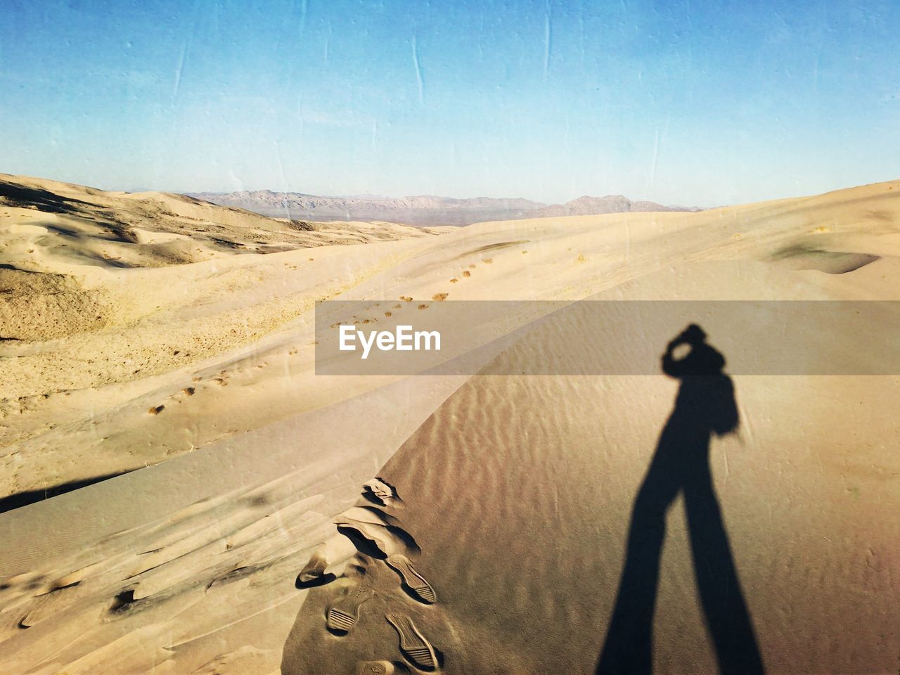 Shadow of man on sand dune against sky