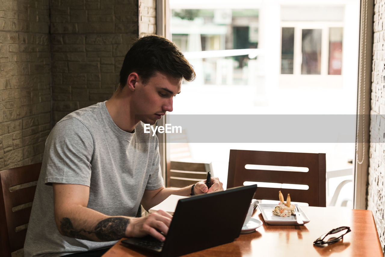 Freelancer sitting at cafe table and browsing laptop