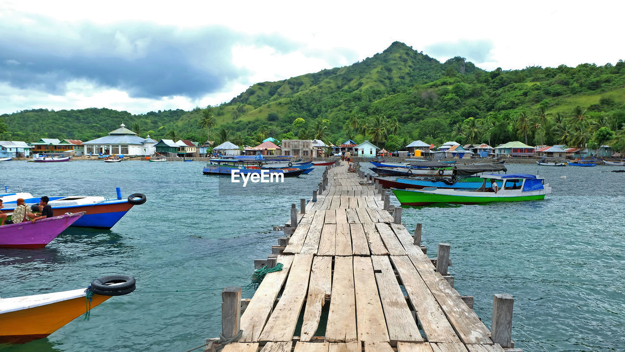 Pier and boats in lake by mountain