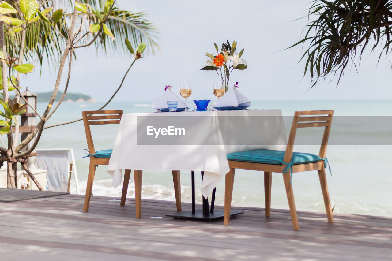 TABLE AND CHAIRS ON BEACH AGAINST SKY