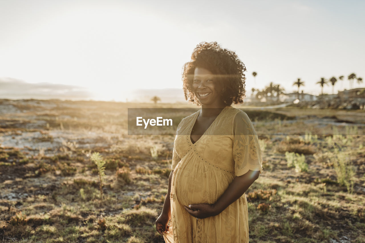 Portrait of pregnant mother in third trimester at beach at sunset