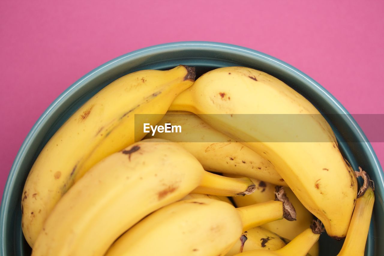 Bananas in a blue bowl on pink background