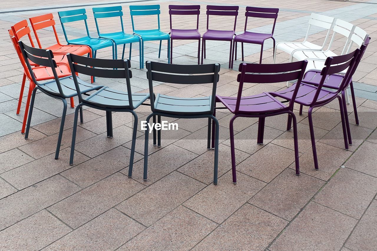 Empty chairs of different colors against tiled floor