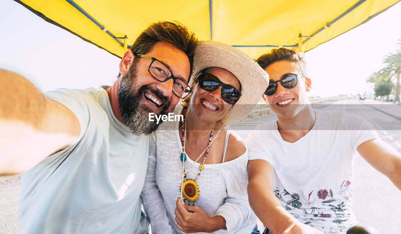 Portrait of happy family sitting in cart against sky