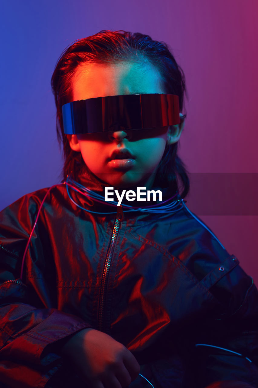 Portrait cyberpunk boy child in vr glasses in blue and red tones. game, virtual reality