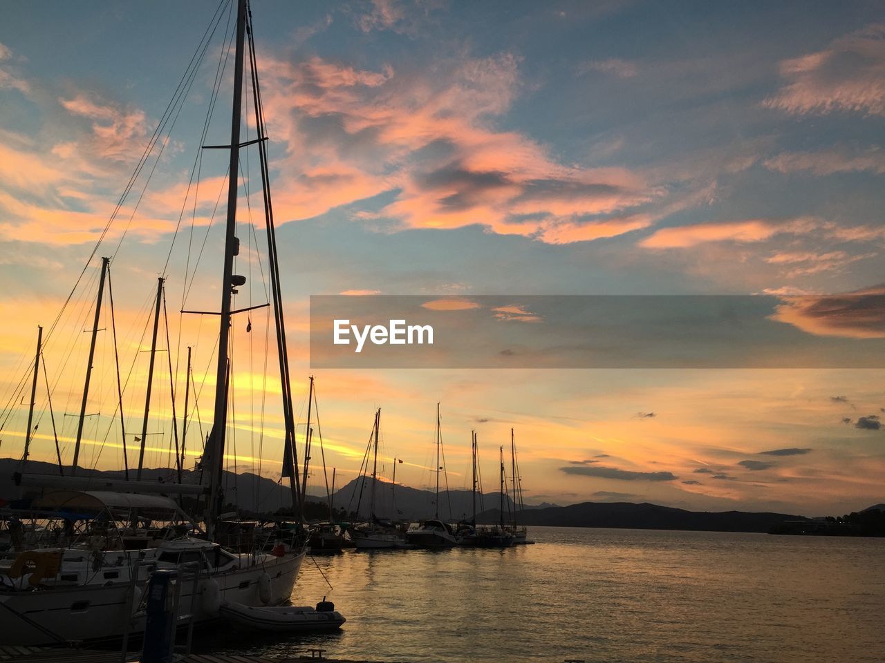 Silhouette sailboats moored on sea against sky during sunset