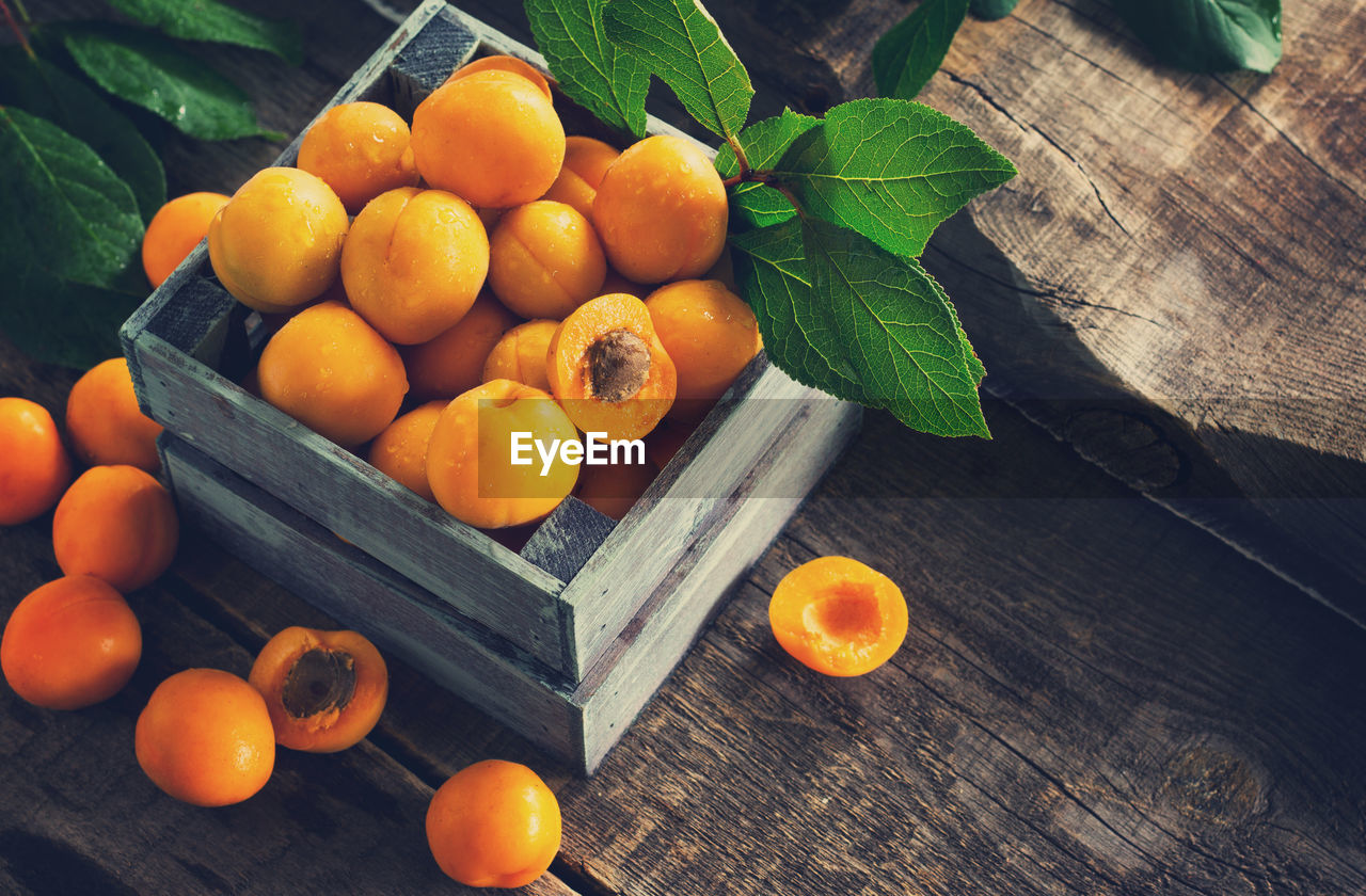 HIGH ANGLE VIEW OF ORANGE FRUITS IN CONTAINER ON TABLE