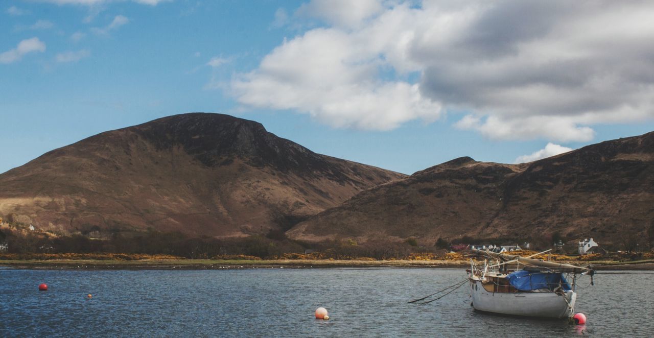 Boats in river with mountain range in background