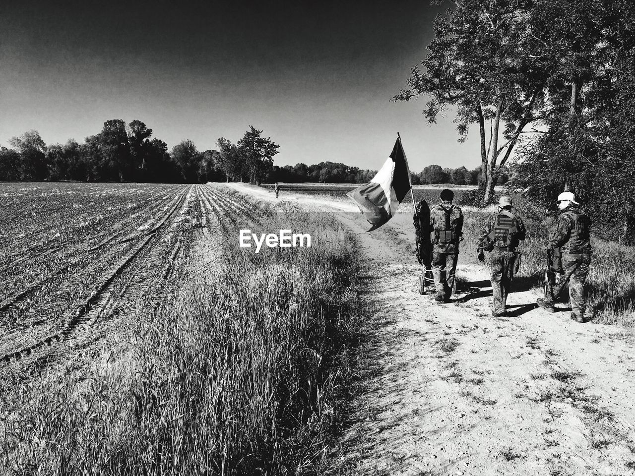 Rear view of soldier walking field against sky