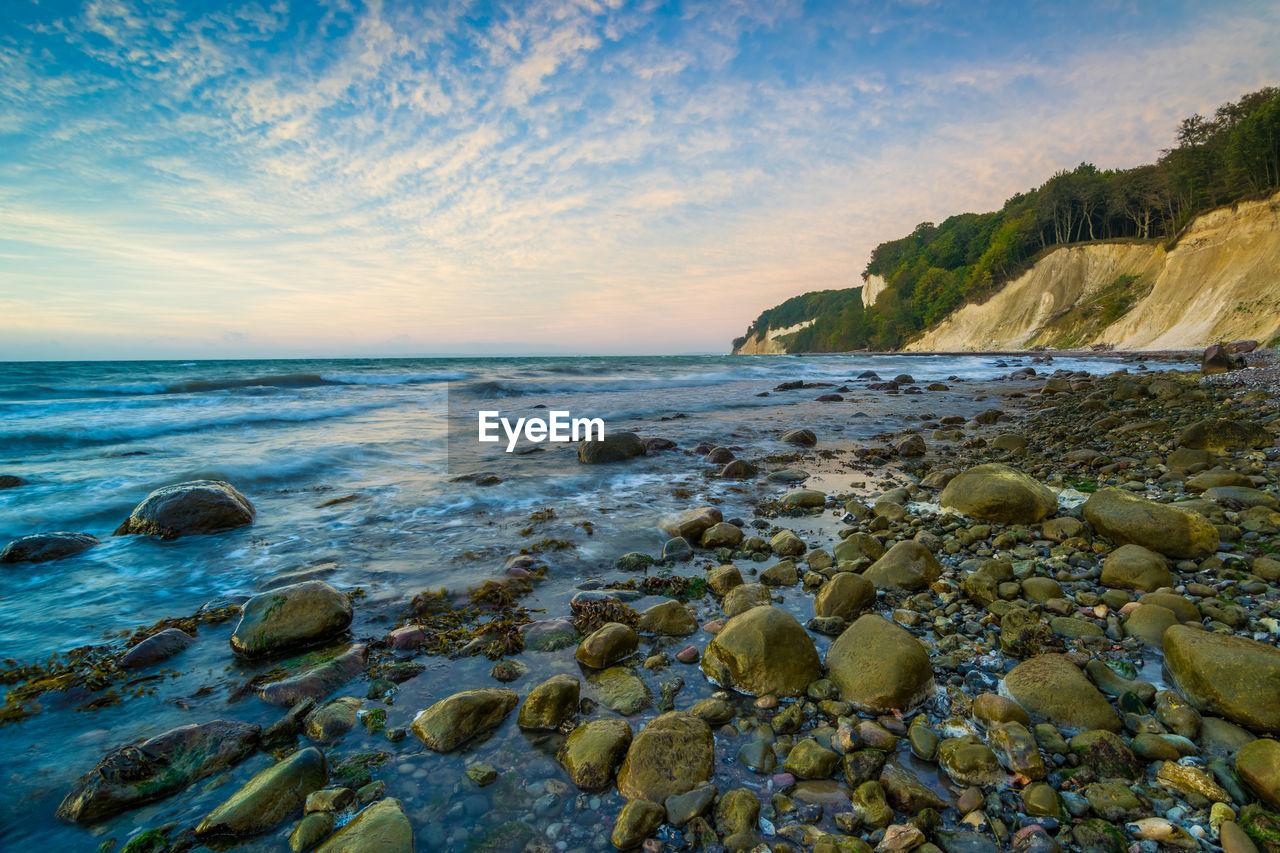 Scenic view of rocky shore against sky during sunset