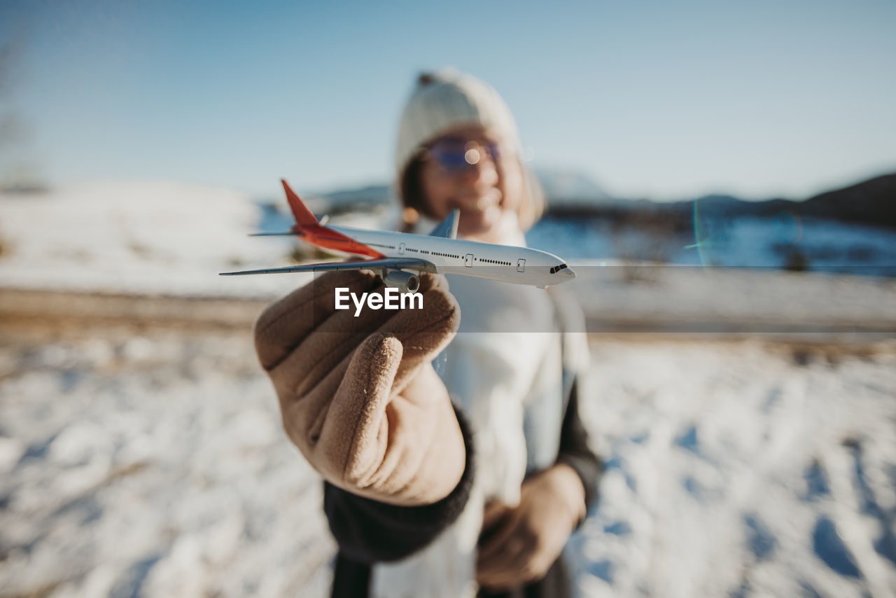 Happy woman holding airplane in hands outdoors in snow
