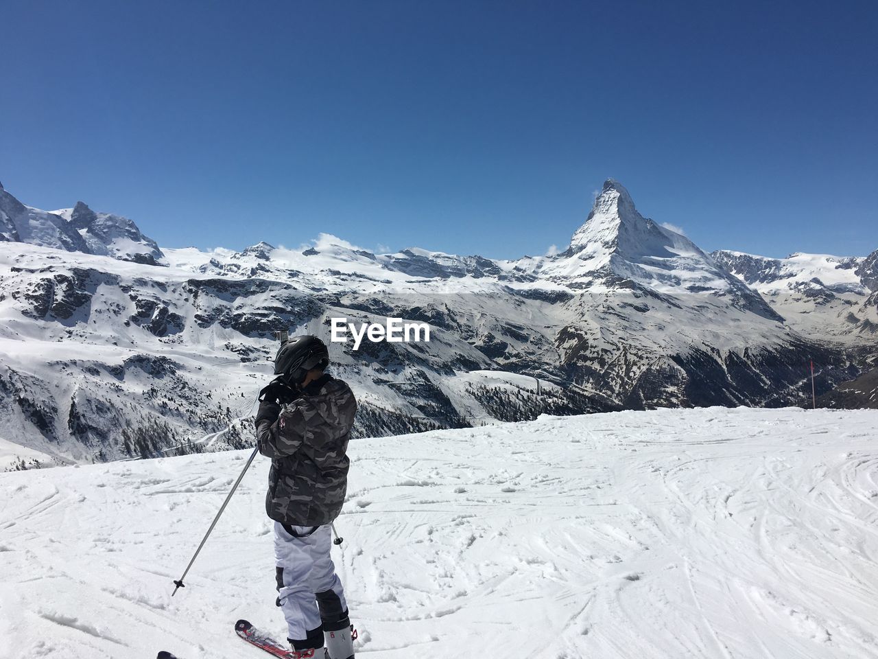 Man skiing on snowcapped mountain against blue sky