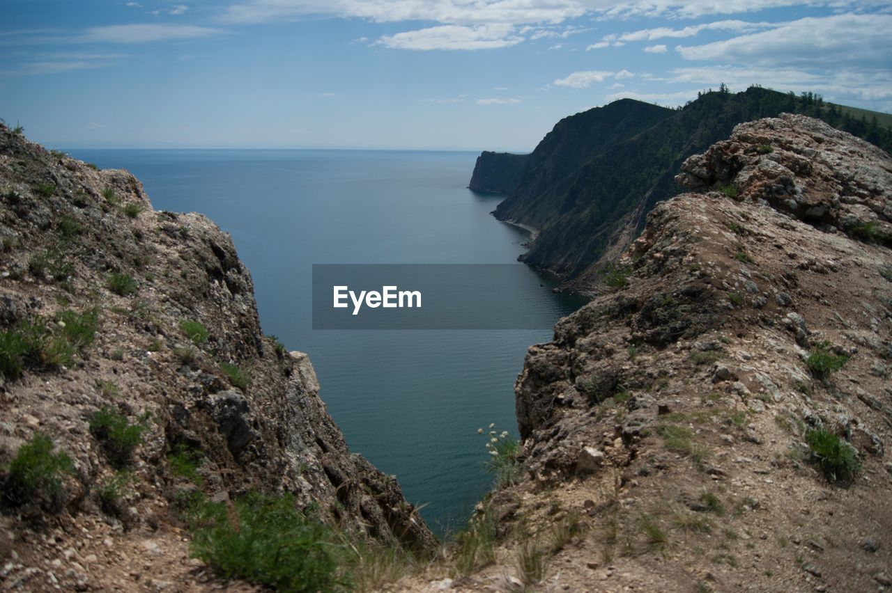 Scenic view of sea by cliff against sky