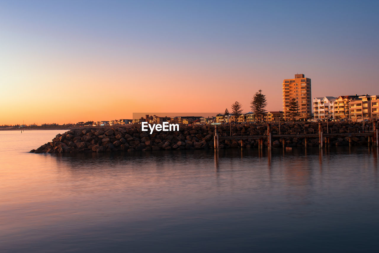 Reflection of buildings in sea at sunset