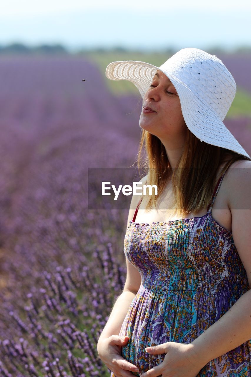 Pregnant woman wearing hat while standing at lavender farm