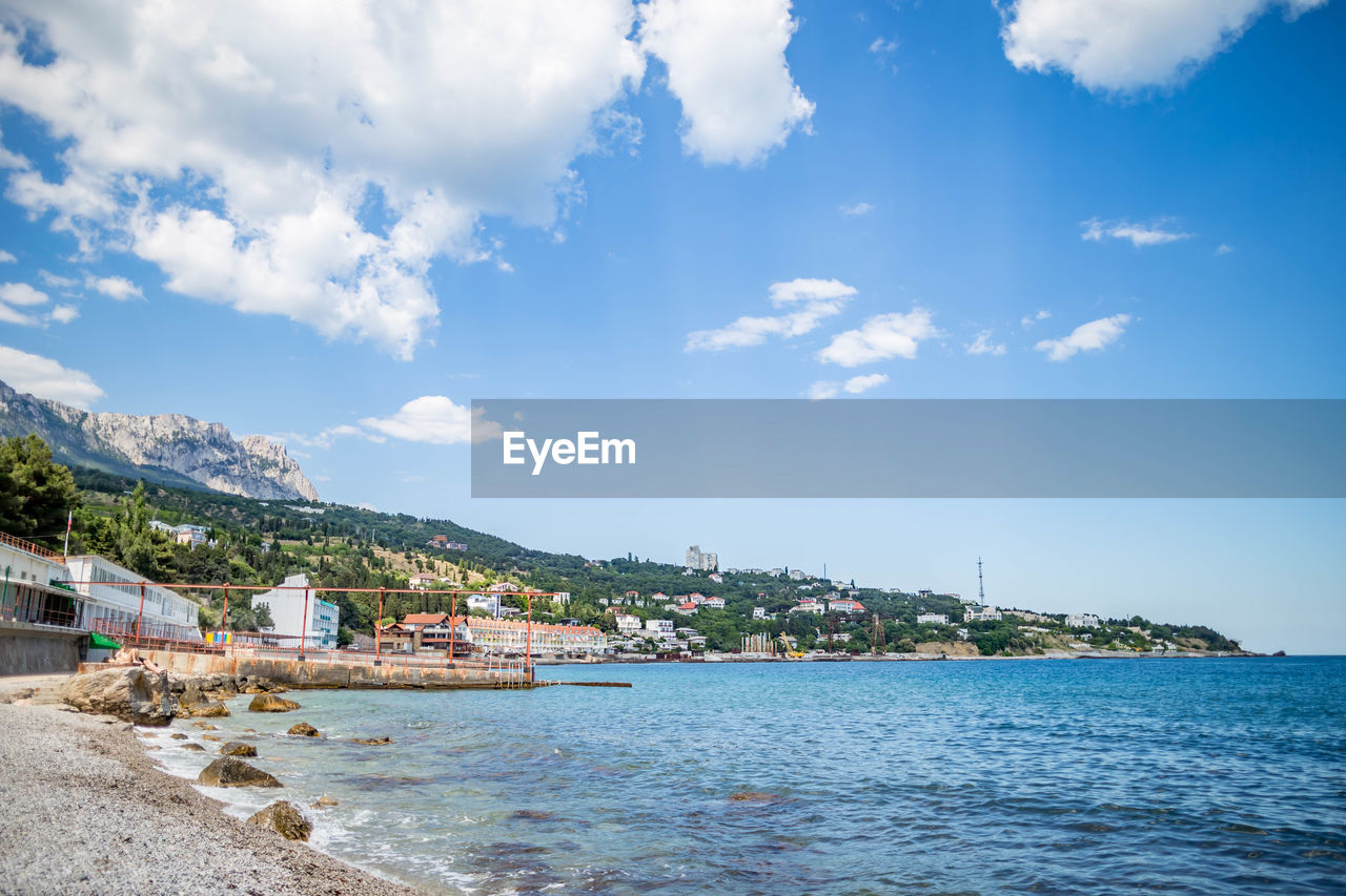 Scenic view of sea by buildings against sky