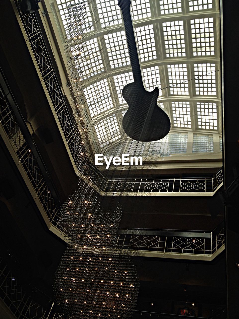 Low angle view of museum atrium interior of ceiling showing unique design of illuminated guitar chandelier 