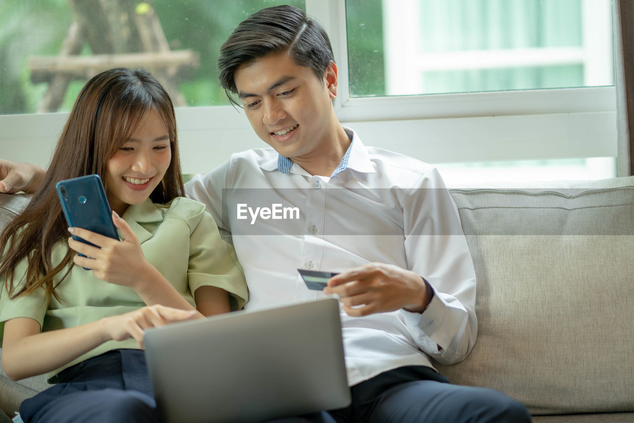 WOMAN USING PHONE WHILE SITTING ON LAPTOP IN OFFICE