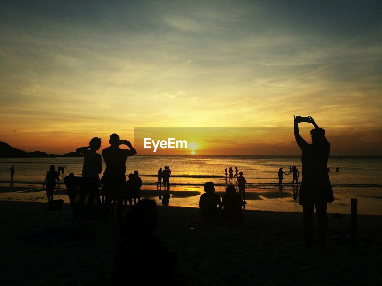 Silhouette people on beach against sky during sunset