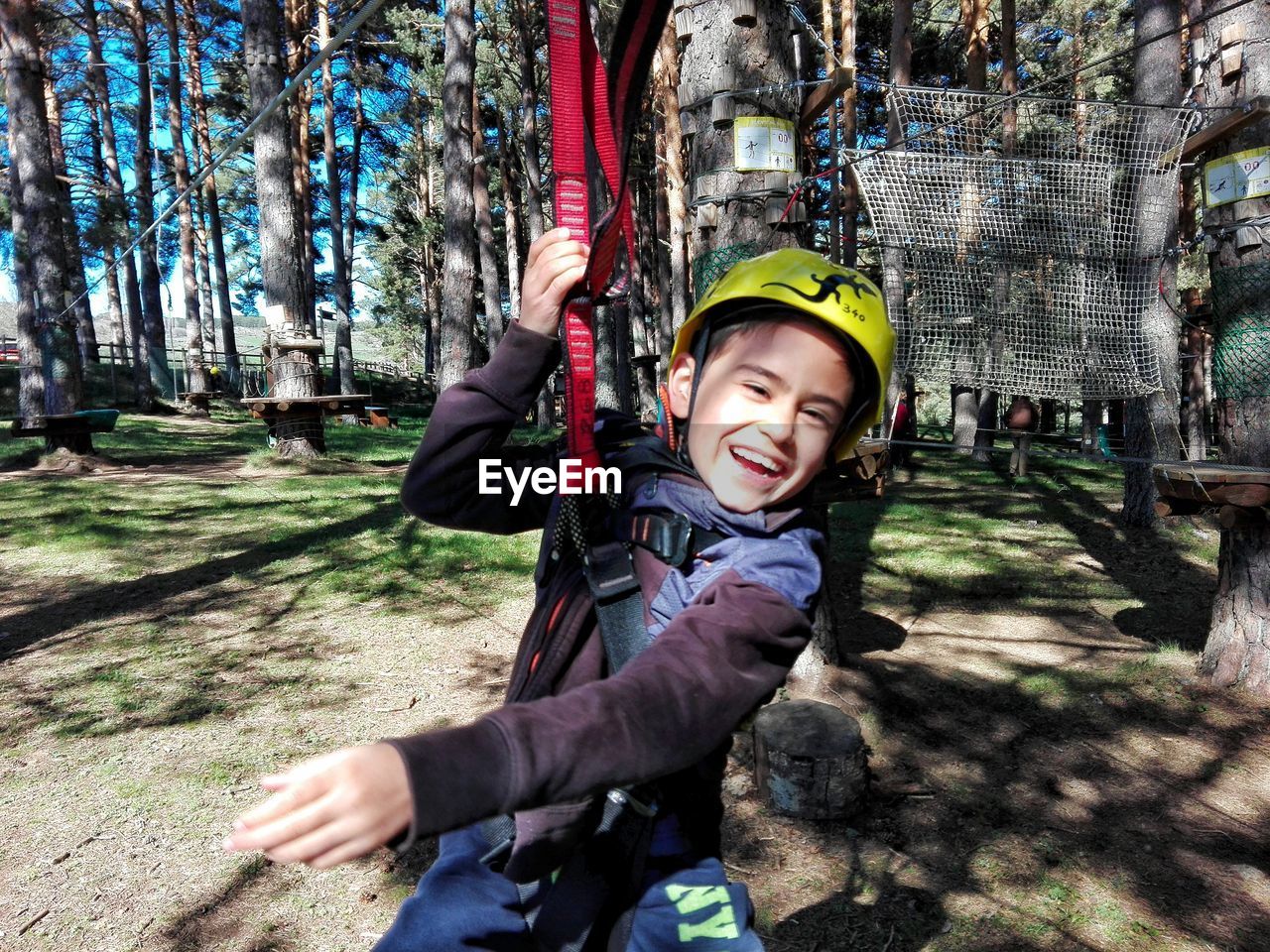 Portrait of smiling boy enjoying zip line in forest