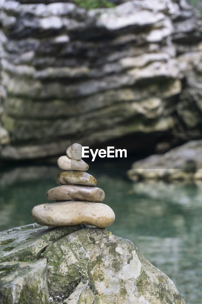 CLOSE-UP OF STONE STACK ON ROCK IN LAKE