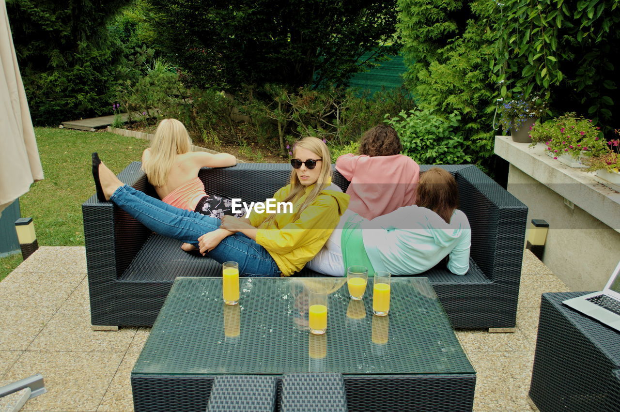 High angle view of friends with juice on table relaxing in yard