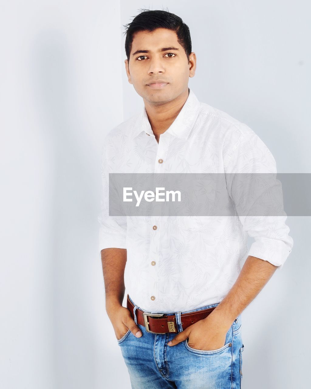 PORTRAIT OF YOUNG MAN STANDING AGAINST WALL