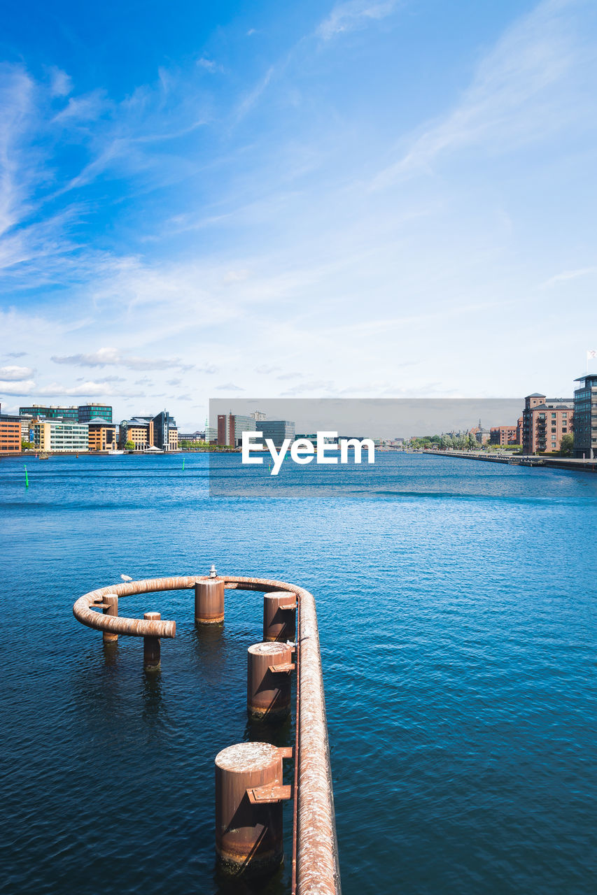 Scenic view of river by buildings against sky