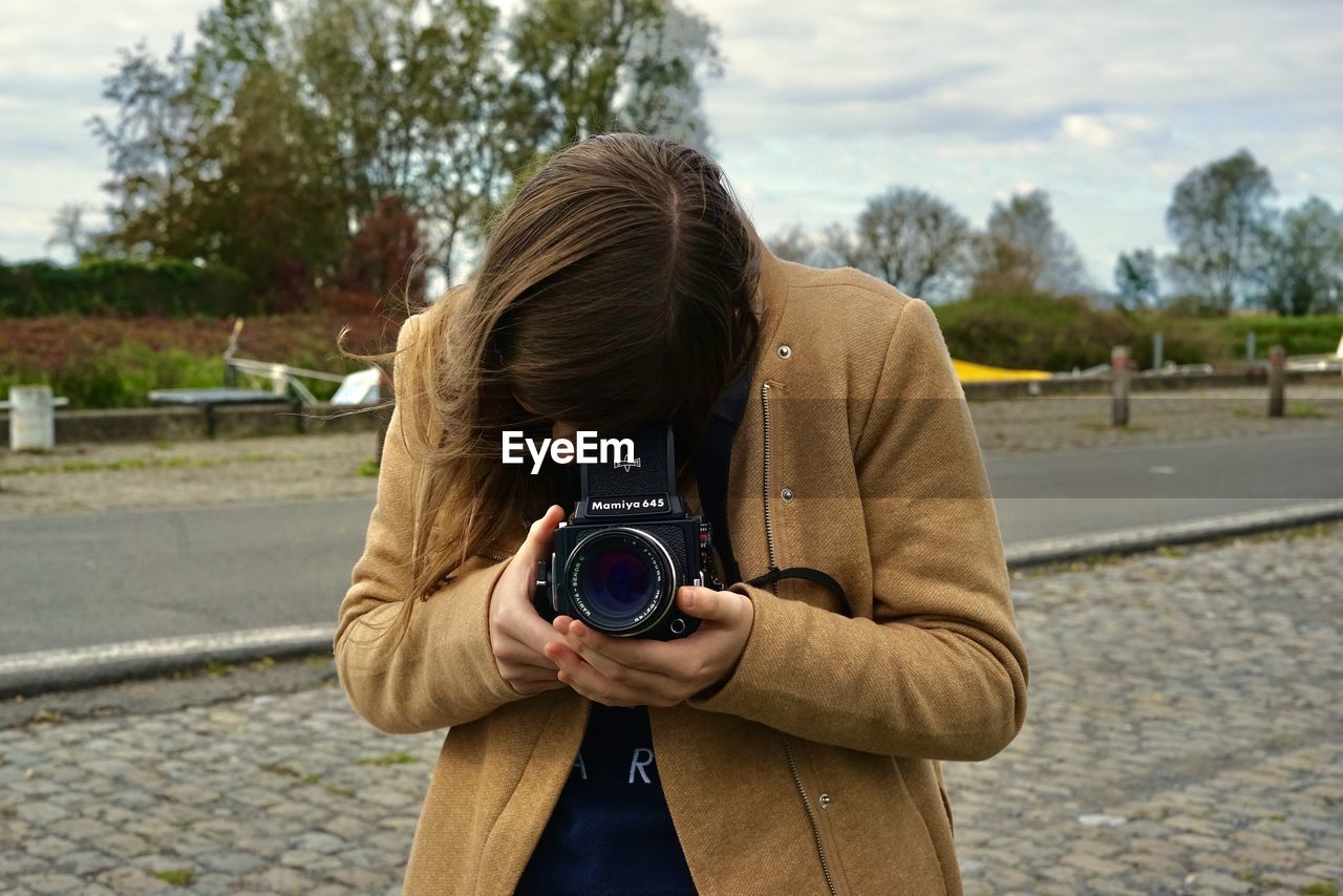 WOMAN PHOTOGRAPHING ON STREET IN CITY