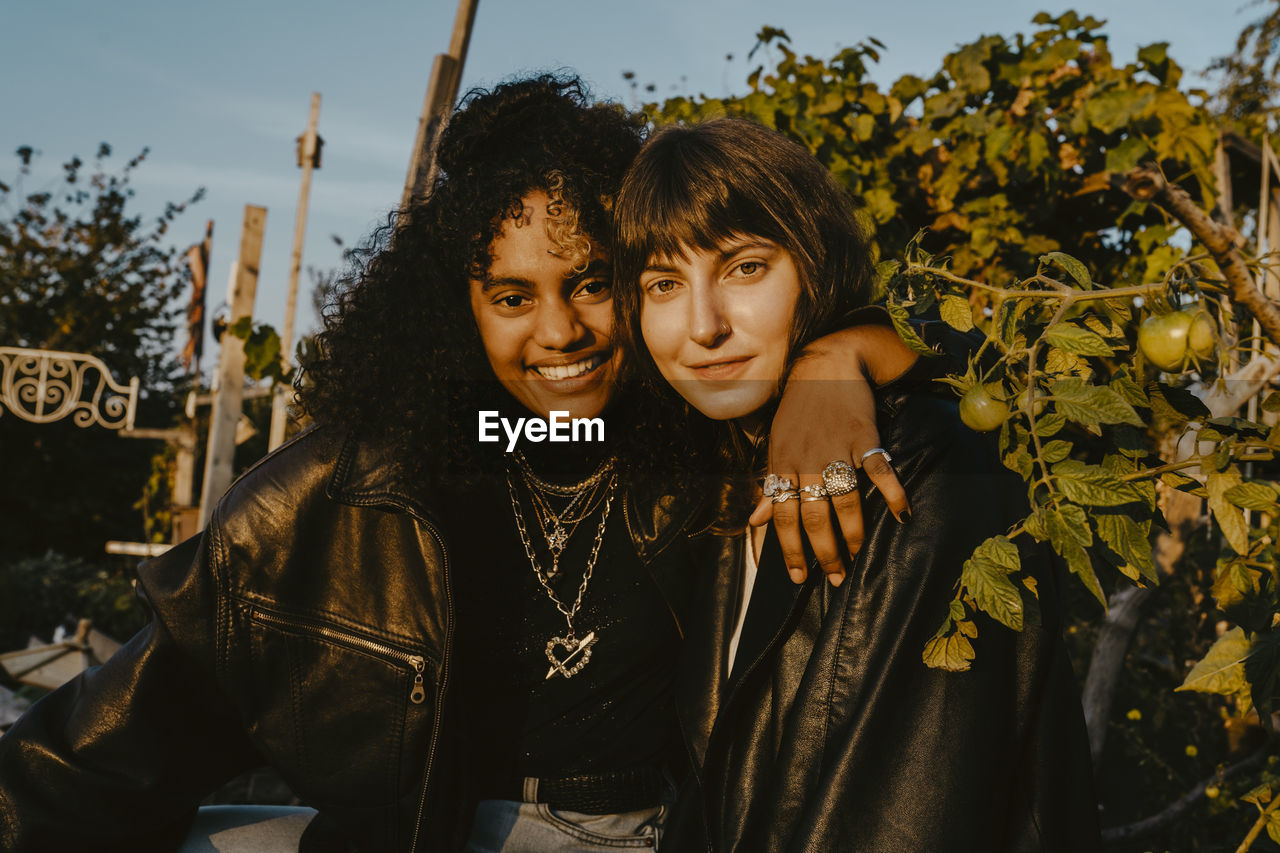 Smiling female friends with arm around in park on sunny day