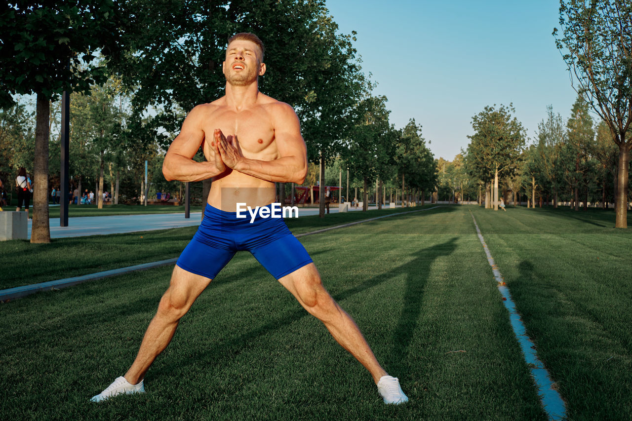 rear view of shirtless man standing on field