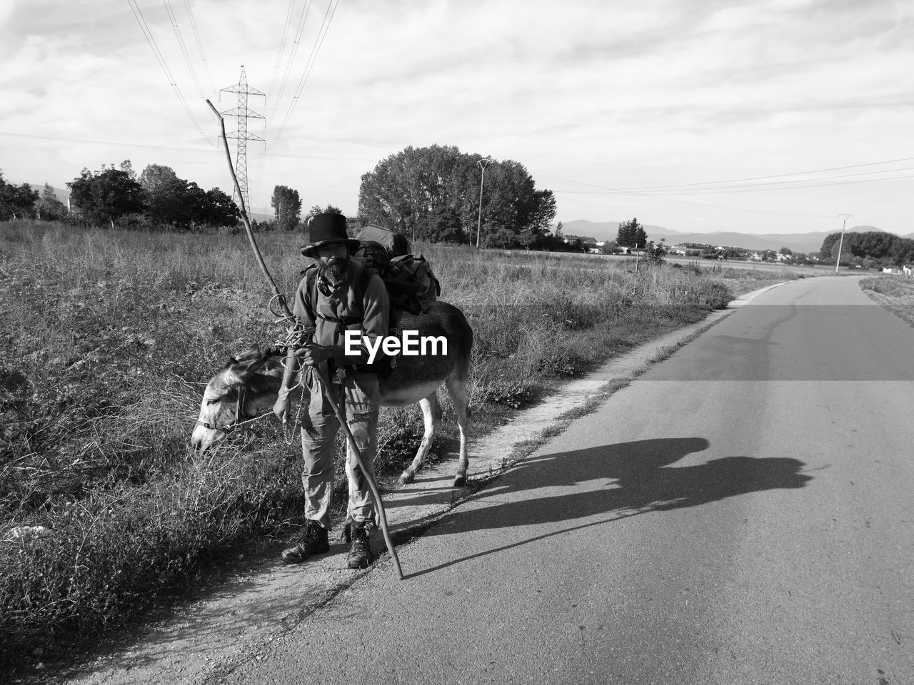 PEOPLE ON COUNTRY ROAD AGAINST SKY