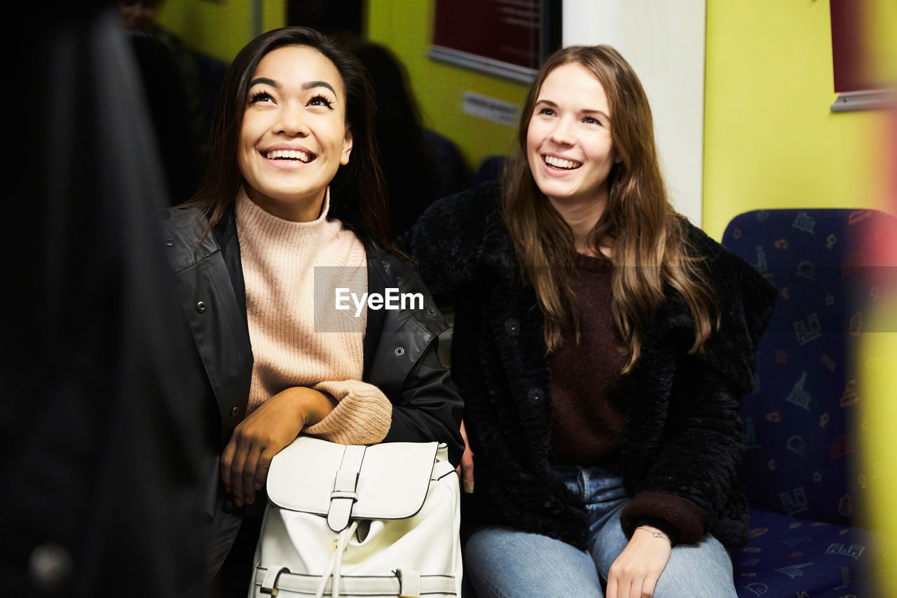 Smiling female friends sitting in train