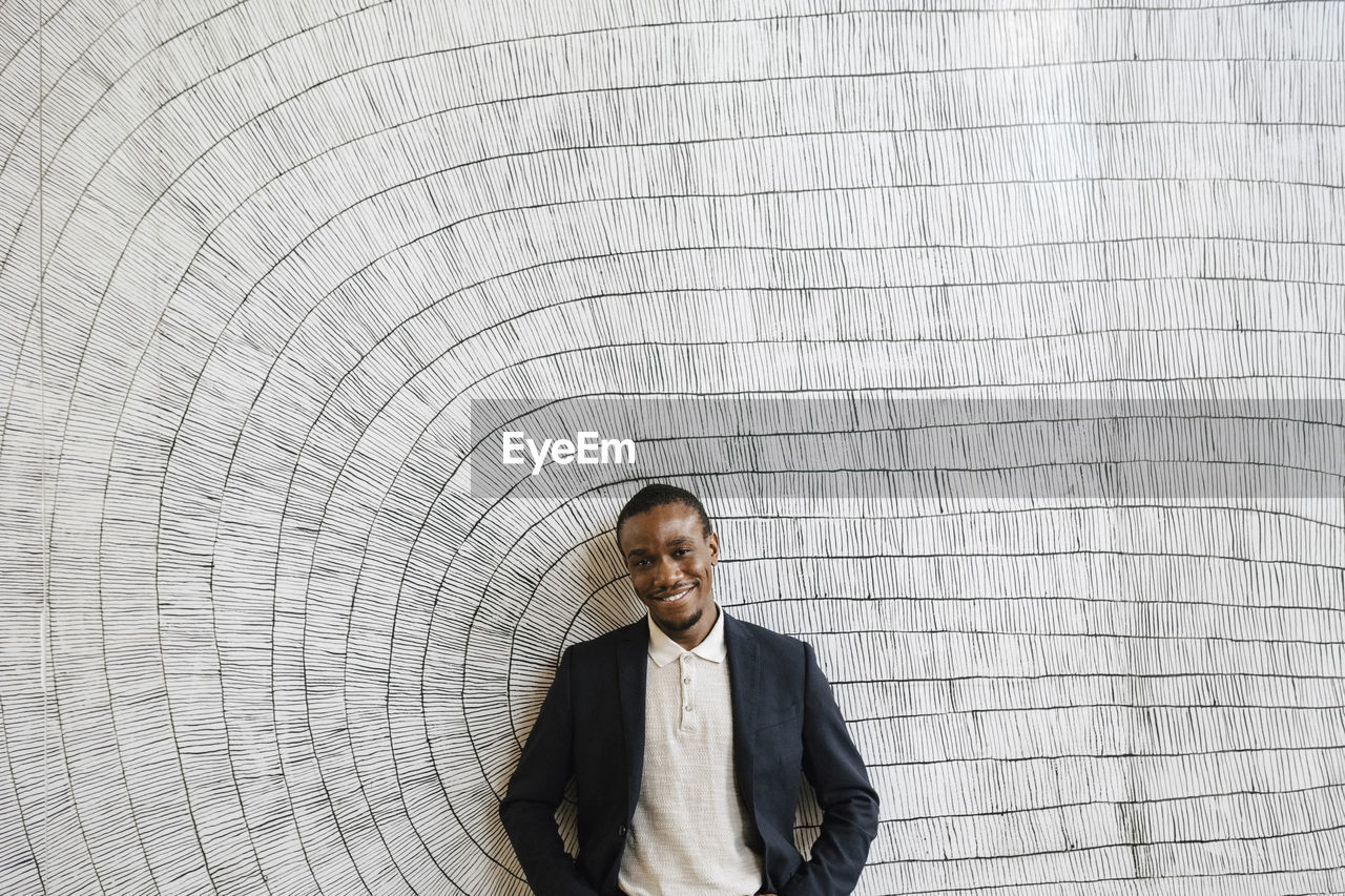 Smiling male professional standing in front of wall at convention center