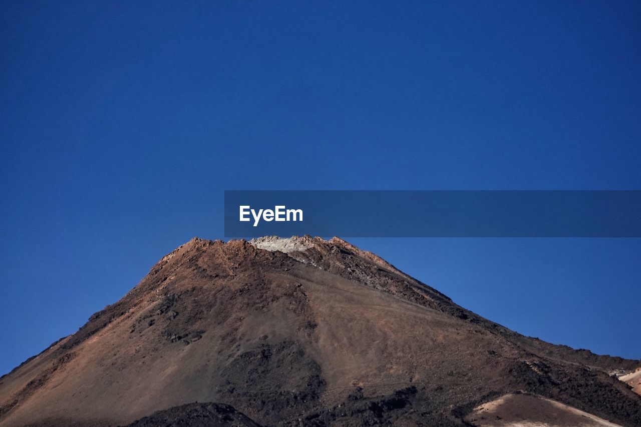 Low angle view of mountain against clear blue sky