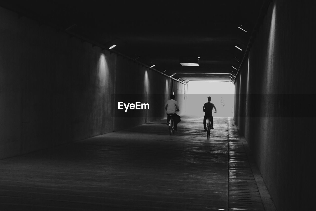 Rear view of man walking in tunnel