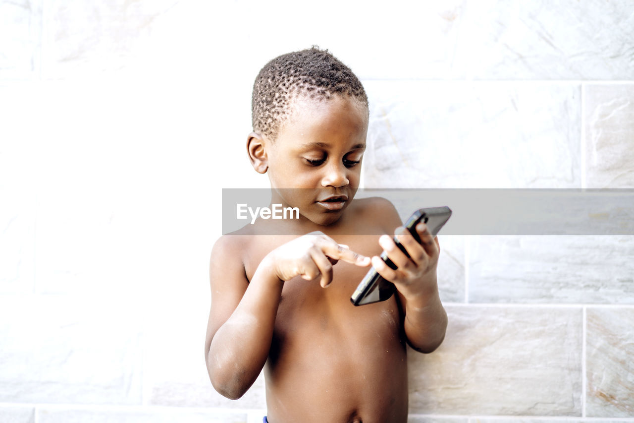 Nice african boy has fun using a mobile phone.