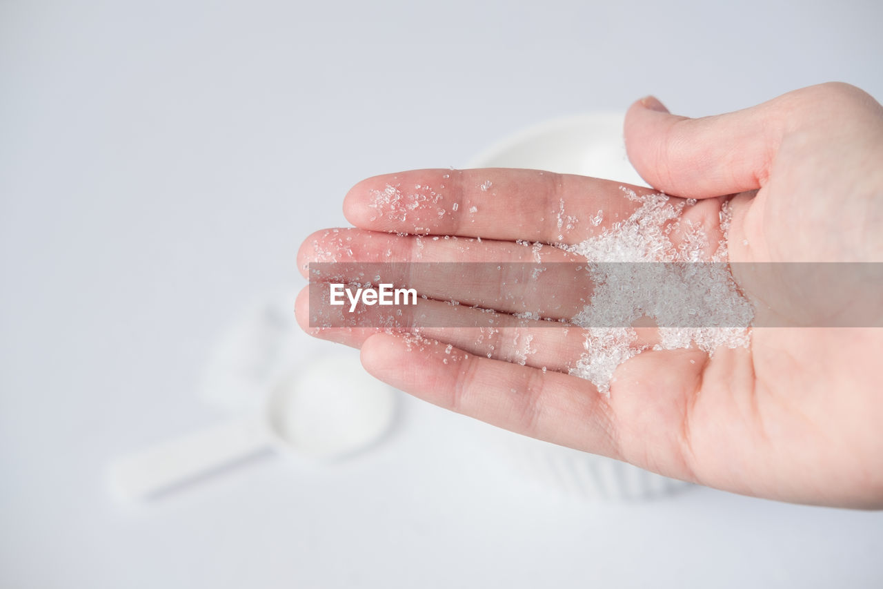 Epsom salt in hand for bath on white background. 