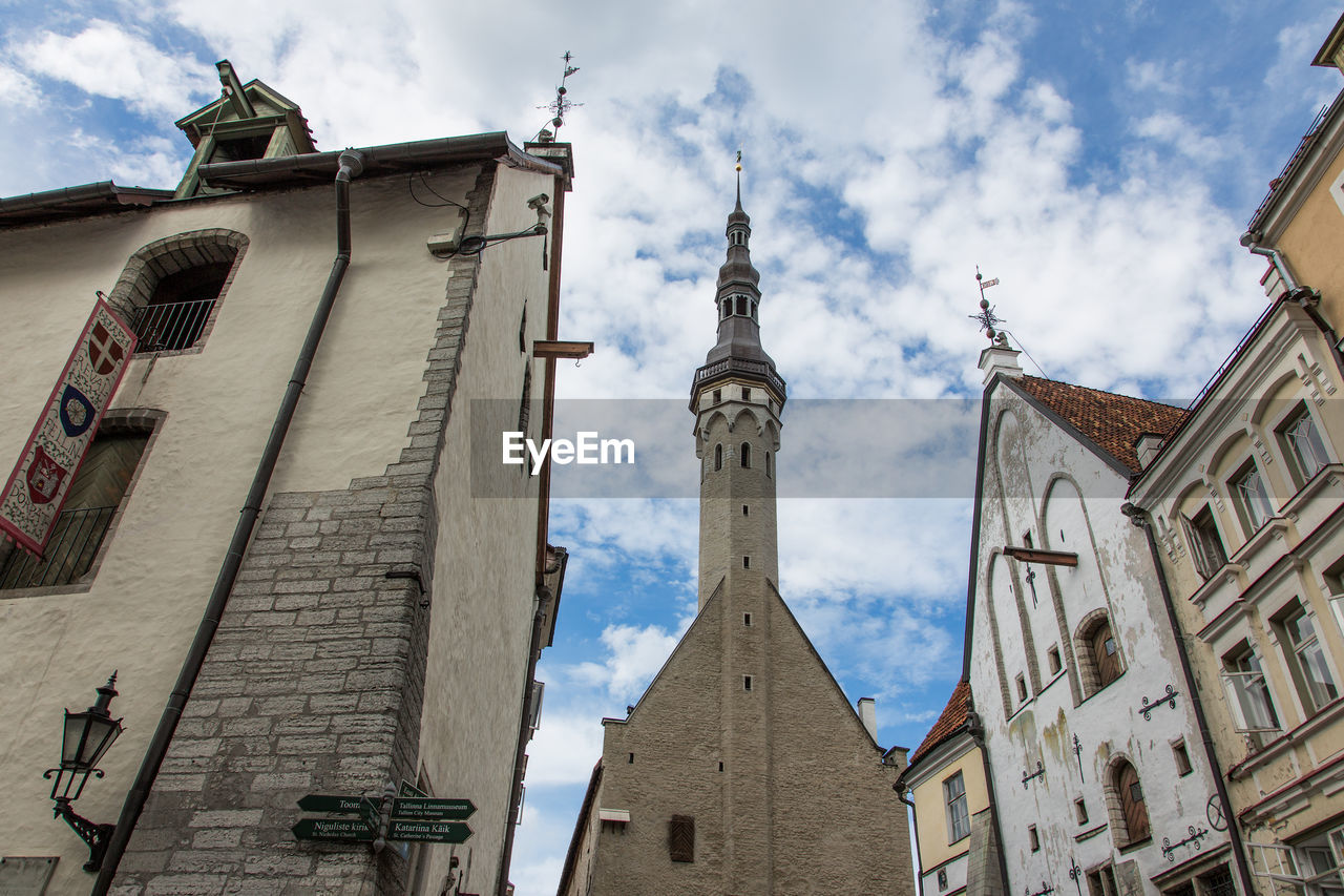 Low angle view of buildings and church against cloudy sky