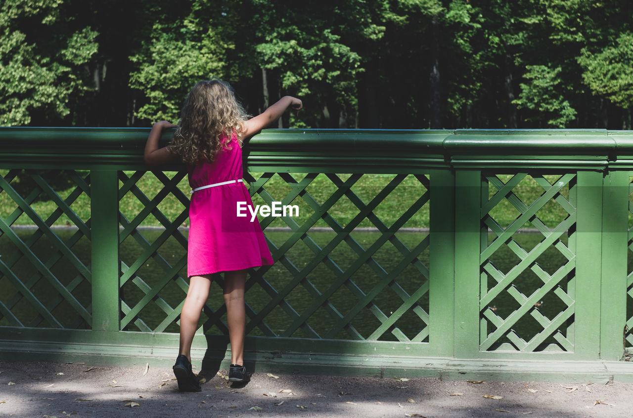 Rear view of girl standing against railing