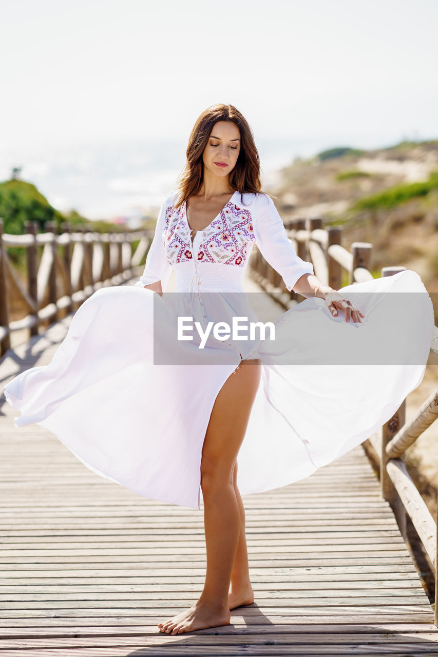 Full length of young woman standing on pier