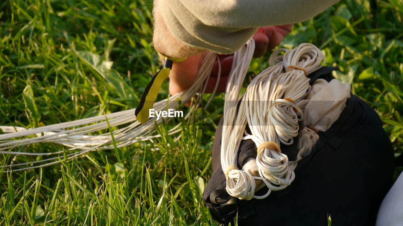 Cropped image of hand holding ropes on grassy field