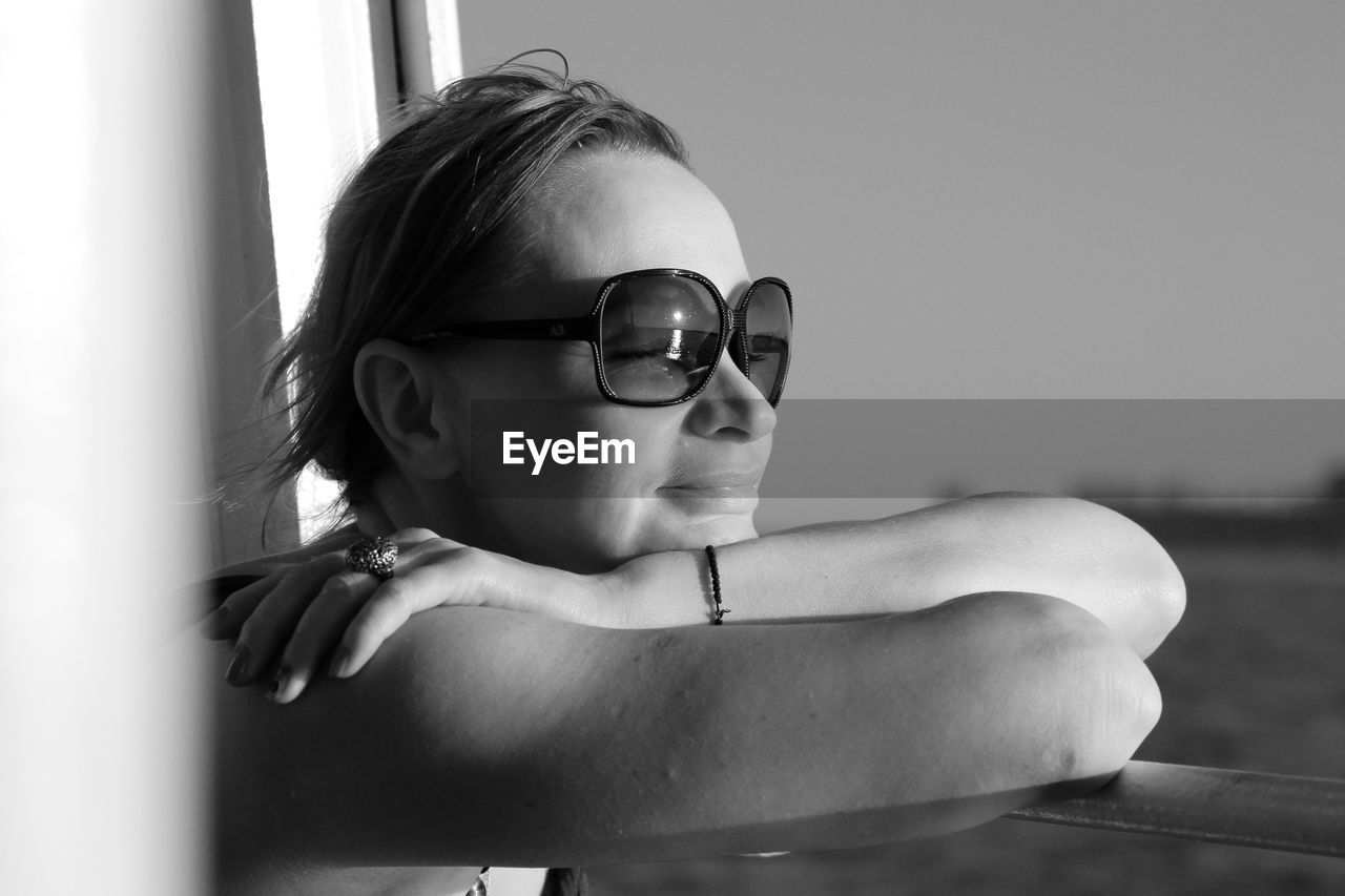 Woman wearing sunglasses leaning on window