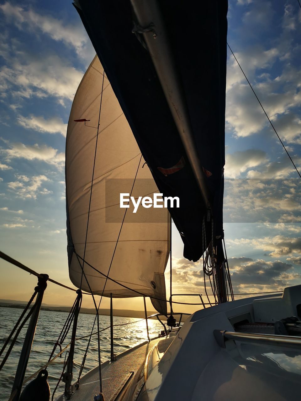 Sailboat sailing on sea against sky during sunset