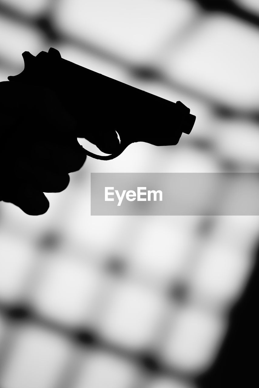 handgun, black and white, black, close-up, weapon, monochrome, monochrome photography, warning sign, social issues, sign, firearm, hand, gun, silhouette, aggression, communication, gun barrel, white, violence, focus on foreground, revolver, crime, security, protection, light