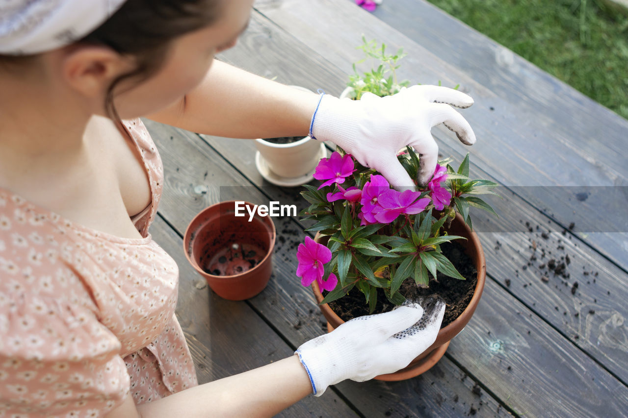  a woman replants an impatiens in a new pot