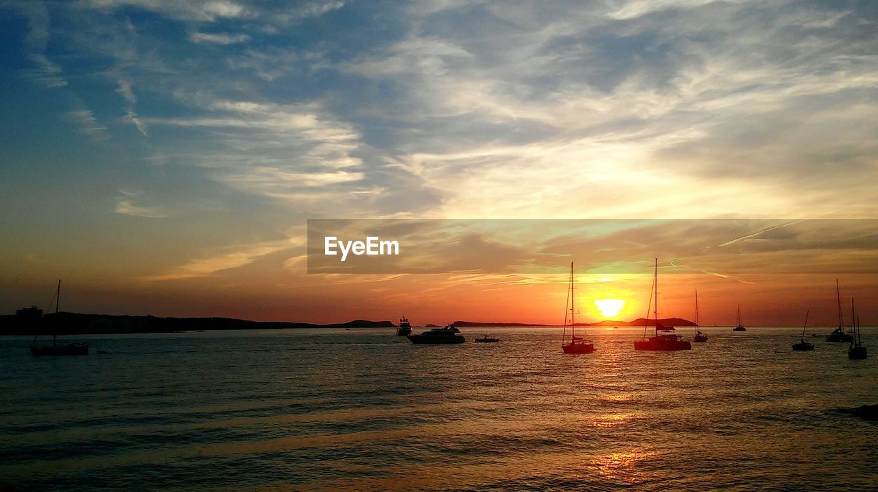 SILHOUETTE BOATS SAILING ON SEA AGAINST SKY DURING SUNSET